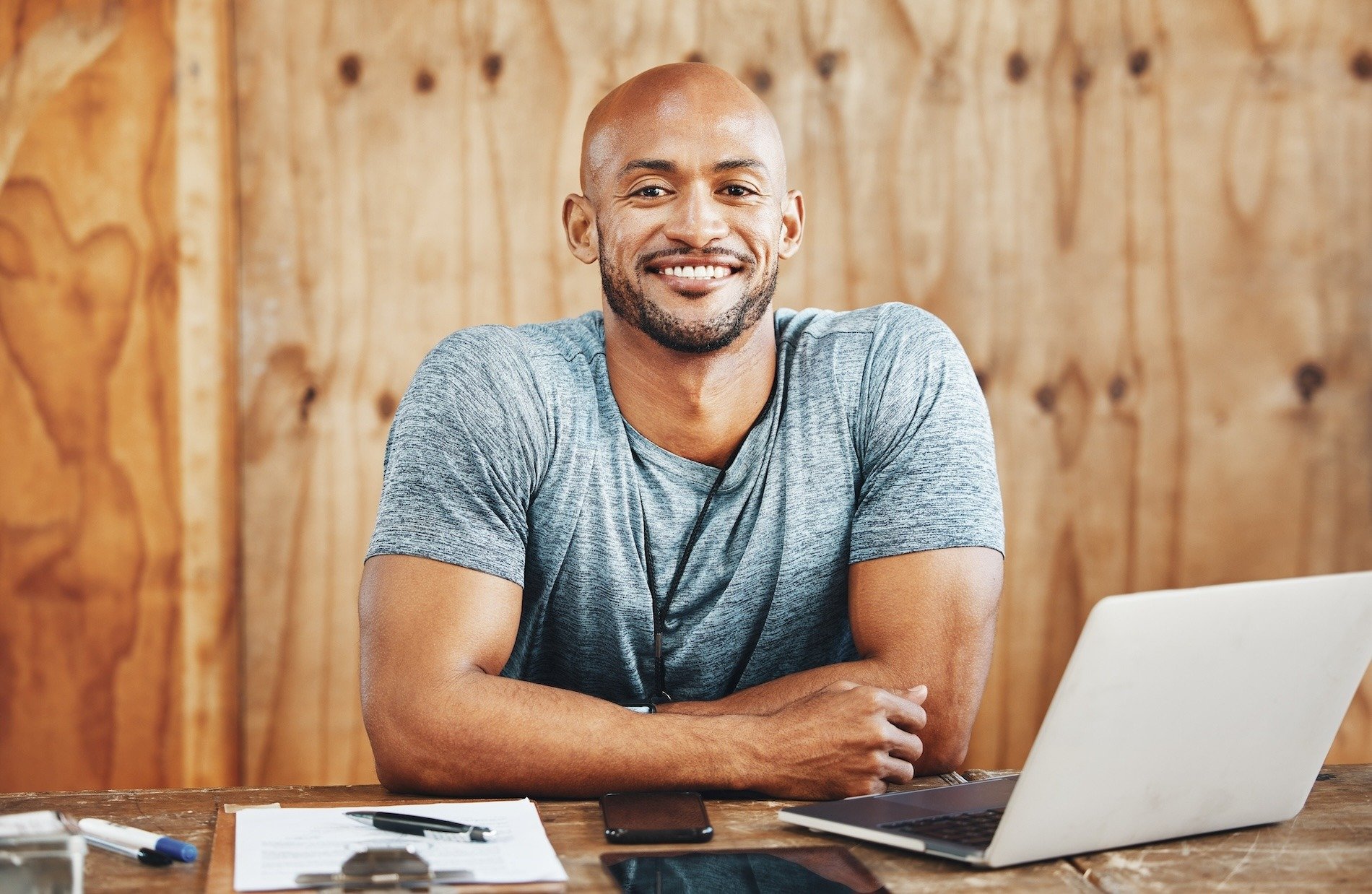 A man in gym kit at a desk with a laptop.