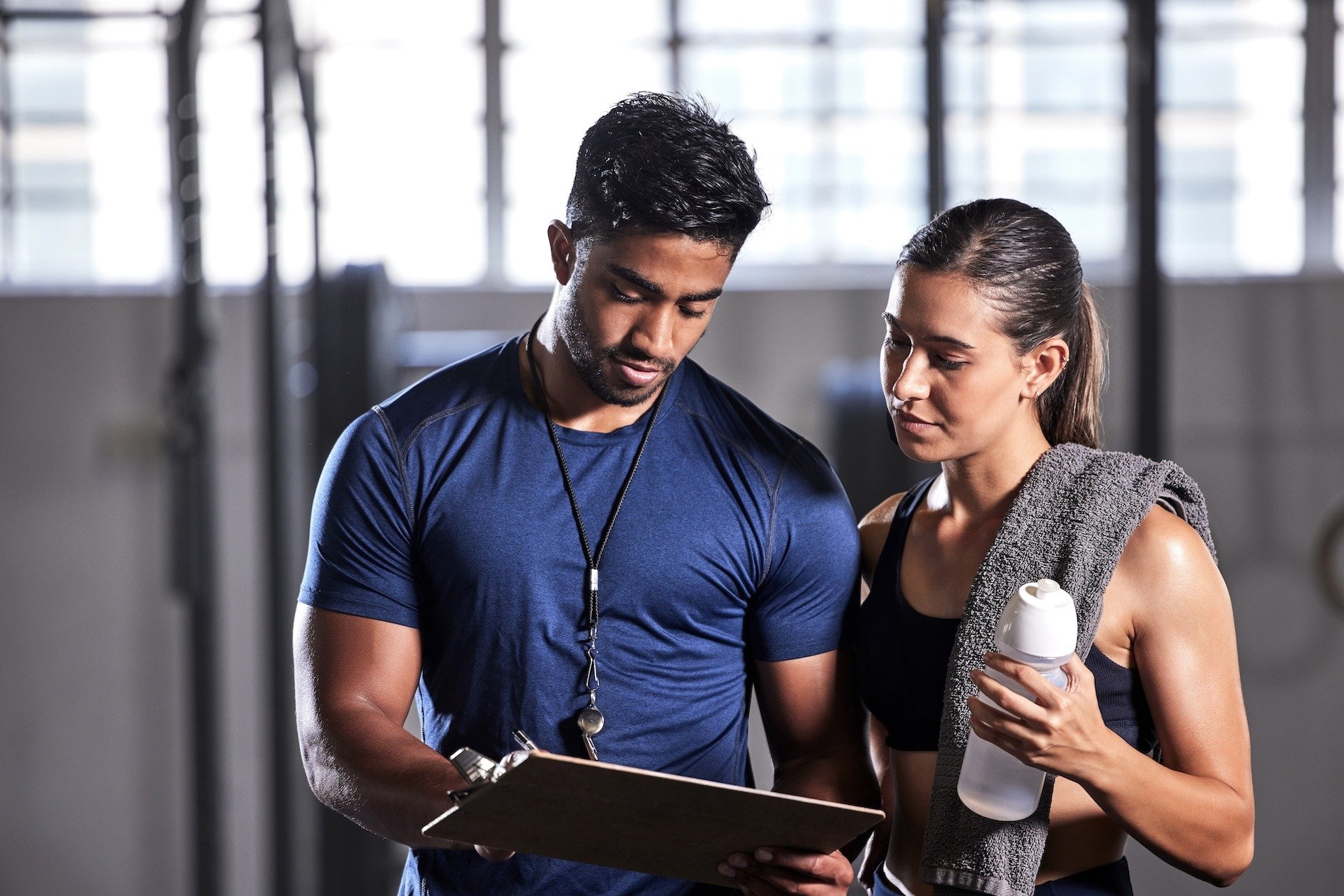 A trainer looking at a clipboard with his client.